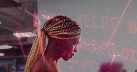 Analyzing woman with ponytail, glasses studying stock charts on screen at office desk with monitors.の写真素材