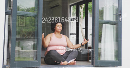 Meditating woman in sportswear on glass door threshold showing floating numerals and fitness...