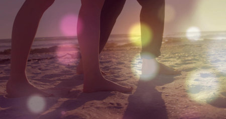 Walking couple's lower legs and bare feet sliding across sandy shoreline at sunset, golden light. Romance, serenity, leisure, harmony, nature, tranquility, adventureの写真素材