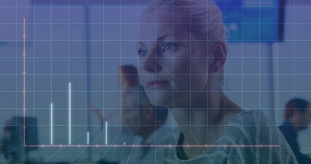 Analyzing woman examining bar and line chart grid at office desk, with computer monitors. Technology, collaboration, analytics, data, professional, digital, businessの写真素材