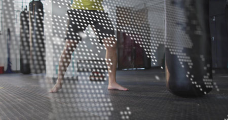 Holding man in green shirt performing fighting stance in gym, with punching bag, world map overlay. Fitness, training, martial arts, combat, strength, agility, digital graphicsの写真素材