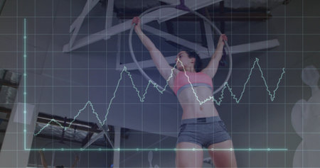 Hanging woman wearing pink sports bra, gray shorts arching from hoop in studio, with graph overlay....