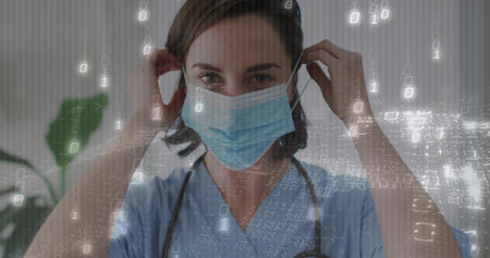 Clinician adjusting surgical mask in clinic, wearing blue scrubs, stethoscope, binary code overlay. Medical, healthcare, digital, technology, professionalism, clinical, futuristicの写真素材