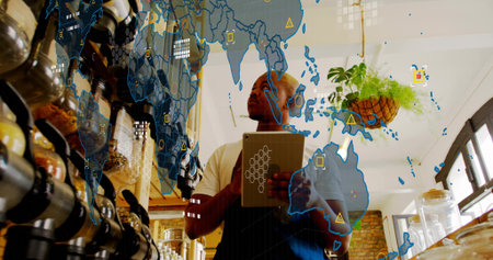 Barista holding tablet and consulting map overlay at coffee counter, wearing dark apron over shirt....