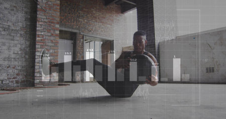 Performing core-strength exercise man bouncing medicine ball in warehouse, with holographic charts. Vitality, fitness, innovation, industrial, architecture, determination, strengthの写真素材
