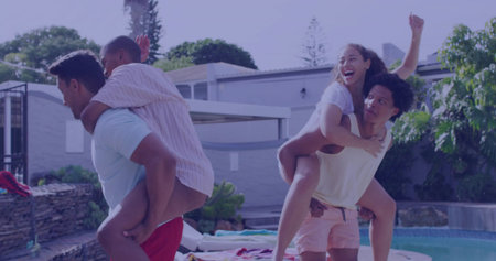 Friends trading piggyback rides on pool deck at backyard gathering, with pool and planter wall. Vibrant, leisure, camaraderie, outdoor, lifestyle, relaxation, festiveの写真素材