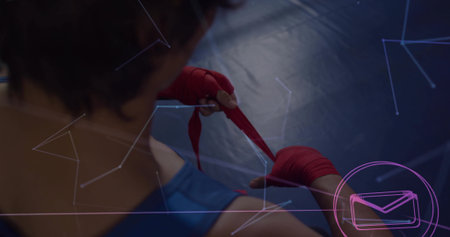 Male athlete in sleeveless top wrapping red hand wraps on gym mat, with graphic overlays. Athlete, training, fitness, combat, protection, digital, technologyの写真素材