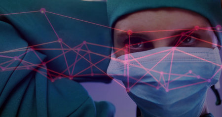 Surgeon in green scrubs, cap adjusting blue glove, mask in operating room with pink network overlay. Medical, healthcare, precision, innovation, clinical, futuristic, professionalismの写真素材