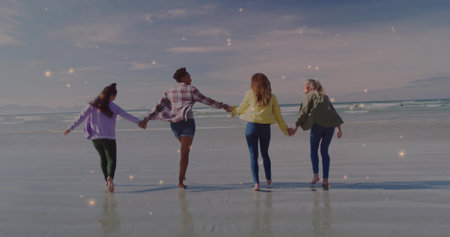 Walking group of four friends holding hands along shoreline, with wet reflective sand, ocean waves. Serenity, companionship, lifestyle, minimalist, leisure, nature, harmonyの写真素材