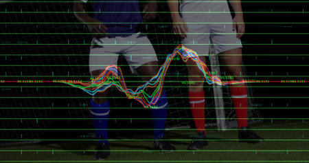Standing two soccer players wearing blue, white jerseys on soccer pitch, goal net, digital overlay....