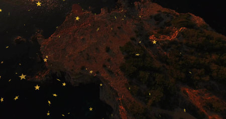 Hovering golden star-shaped graphics above rocky coastal cliff at night, with shrubs and dark water. Seascape, celestial, surreal, dramatic, minimalist, tranquility, nocturnalの写真素材