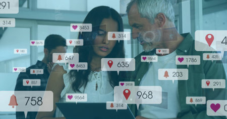 Four marketing professionals collaborating on tablet analyzing social media icons in modern office. Collaboration, analytics, digital, technology, teamwork, modern, professionalの写真素材