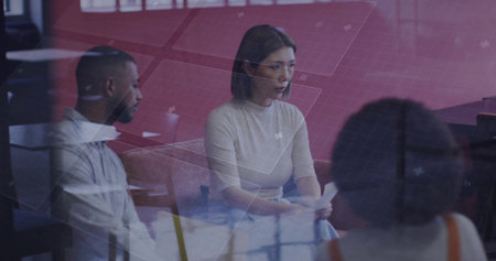 Holding papers woman wearing light-tan top discussing agenda in conference room, with grid graphics....