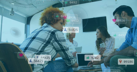 Collaborating four professionals analyzing social media metrics in office using laptop smartphone. Teamwork, innovation, digital, contemporary, communication, data, workplaceの写真素材