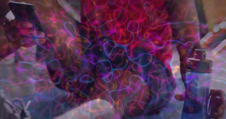 Sitting man wearing red top holding smartphone and blue vape device on couch, neon light trails....