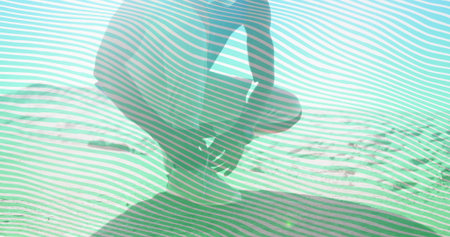 Kneeling shirtless man in shorts gazing across rippled sand dune under bright sun, with lens flare. Adventure, exploration, serenity, minimalist, landscape, wellness, contemplativeの写真素材