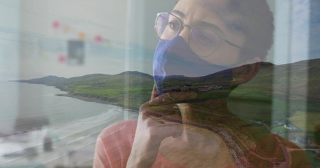 Leaning woman wearing blue mask and round glasses by window overlooking coastal hills, copy space. Contemplation, reflection, serenity, modern, wellness, architecture, freshの写真素材