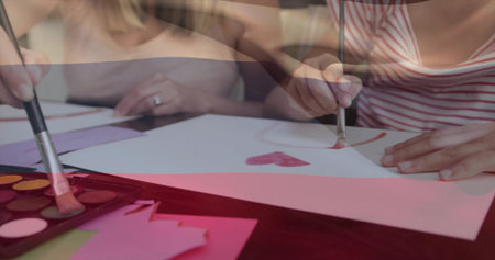 Painting girl in red tank top painting heart at craft area, with watercolor palette, copy space. Family, creativity, artistry, childhood, education, relaxation, inspirationの写真素材