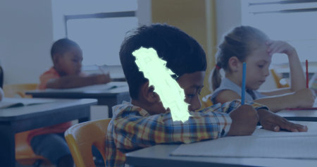Writing African American boy in plaid shirt leaning over desk in classroom, with pencils and paper. Scholarly, focus, concentration, education, learning, academic, interiorの写真素材