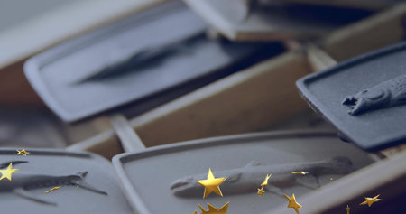 Displaying gray rectangular trays holding small fish-shaped casts on wooden rack at workshop bench. Craft, organization, miniature, display, artistry, texture, craftingの写真素材