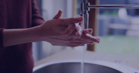 Washing soapy hands under running water at kitchen stainless steel basin, with chrome faucet lather. Hygiene, cleanliness, wellness, domestic, modern, lifestyle, minimalismの写真素材