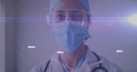 Standing doctor wearing mask cap goggles and coat in clinic, with stethoscope and digital overlay. Medical, healthcare, futuristic, technology, professional, clinical, cleanの写真素材
