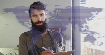 Writing bearded kitchen manager jotting notes on clipboard at restaurant kitchen, with world map. Professional, culinary, modern, hospitality, workspace, creative, organizedの写真素材