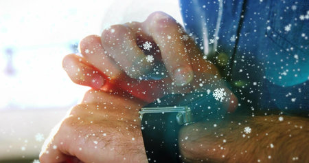 Adjusting denim clad wrist tapping black-banded rectangular smartwatch in blur, snowflake overlay. Technology, winter, fashion, digital, accessories, minimalism, eleganceの写真素材
