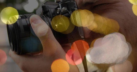 Photographer holding DSLR camera and adjusting zoom lens in night event location, with bokeh lights....