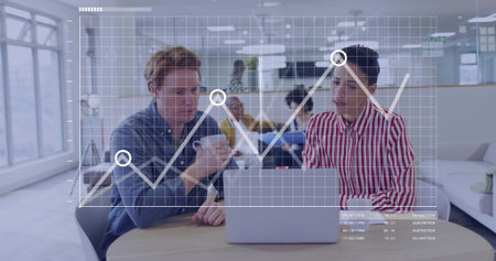 Collaborating colleagues analyzing digital graph overlay at co-working lounge, with silver laptop. Business, innovation, modernity, networking, teamwork, creative, vibrantの写真素材