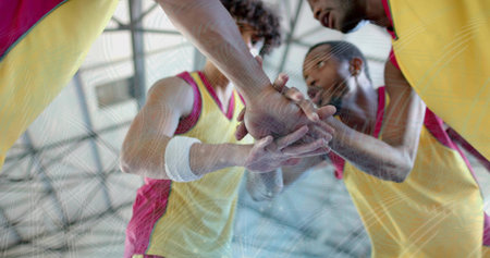 Huddling male basketball players stacking hands inside gym, with yellow red jerseys and wristbands. Team, camaraderie, athleticism, determination, motivation, unity, vigorの写真素材