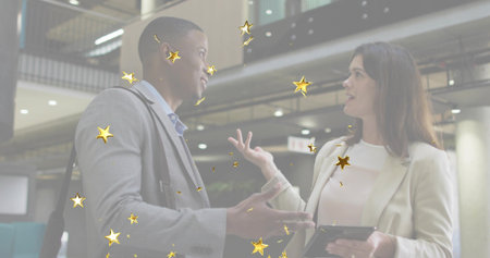 Discussing two professionals reviewing project on tablet in office atrium, golden star overlays....