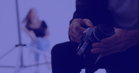 Hands adjusting mirrorless camera in studio with light stand, model wearing black top, copy space. Professional photography, studio portrait, fashion shoot, equipment, lighting, creative processの写真素材