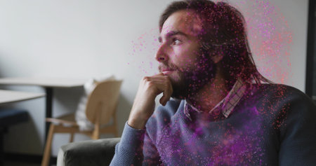 Contemplating man wearing sweater, collared shirt sitting on sofa in lounge. Introspection,...