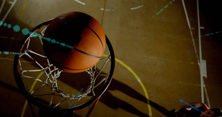 Basketball hoop showing ball passing through net on gym court lines, shooter's shadow, copy space. Sports, athleticism, competition, gymnasium, dynamic, movement, actionの写真素材