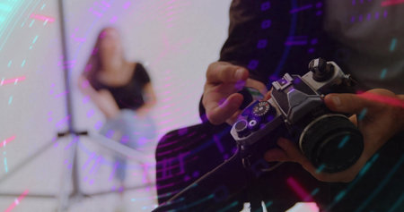 Photographer holding vintage film camera and adjusting dials in studio, with colored lights. Creative lighting, professional photographer, vintage equipment, portraiture, studio environmentの写真素材