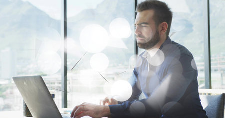 Typing man wearing button-down shirt at office desk by windows, with laptop and mug, copy space....