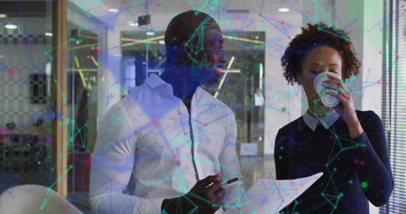 Two coworkers reviewing document in office workspace with pen, coffee cup and network graphics. Professional, collaboration, modern, connectivity, corporate, innovative, workspaceの写真素材