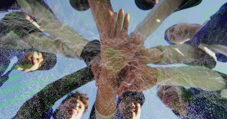 Huddling eight female players in sportswear outdoors under clear blue sky, stacking hands at center....