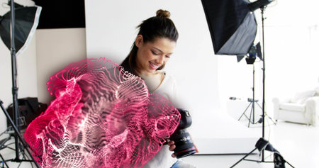 Examining woman photographer reviewing images on DSLR camera in studio, with pink wave overlay....