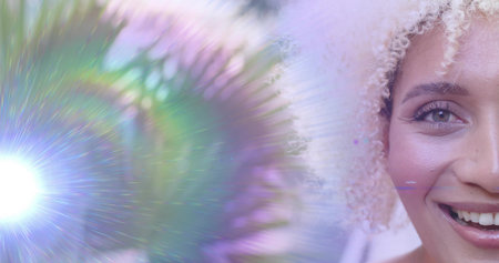 Highlighting adult woman's face capturing colorful lens flare patterns in studio set, copy space. Portrait, beauty, lighting, abstract, glamour, fashion, vibrantの写真素材