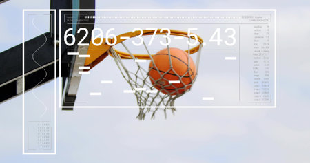 Orange basketball passing through hoop net in outdoor court, showing translucent overlay panels. Sports, technology, innovation, digital, data, analytics, modernの写真素材