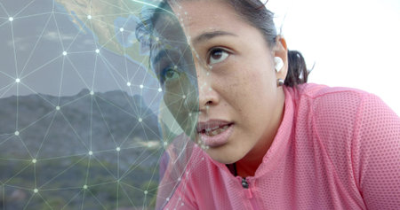 Runner gazing upward on trail with pink jacket, white earbuds, digital network overlay, copy space....