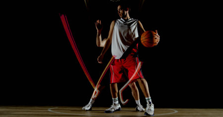 Dribbling basketball player pivoting rapidly on gym court, with orange basketball and white jersey. Sports, competition, agility, strength, teamwork, athleticism, choreographyの写真素材