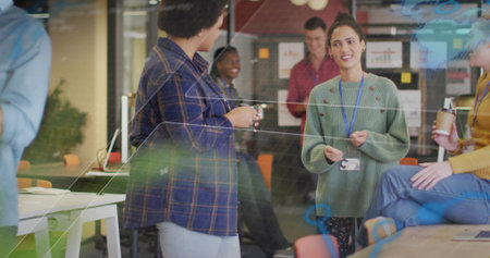 Gesturing woman in green sweater wearing lanyard leading brainstorming at office, with sticky notes....