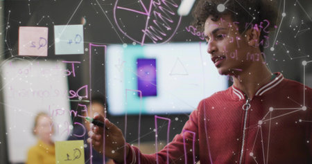 Writing developer in red jacket on glass board with sticky notes in meeting room, display screen. Collaboration, innovation, brainstorming, teamwork, digital, creative, problem-solvingの写真素材