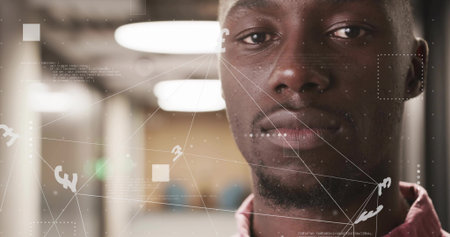 Standing African American man wearing pink shirt in office corridor, with network overlay....