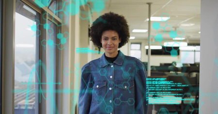 Woman wearing denim jacket viewing holographic data in office corridor, hexagon molecular graphics. Futuristic, technology, innovation, professional, modern, science, digitalの写真素材