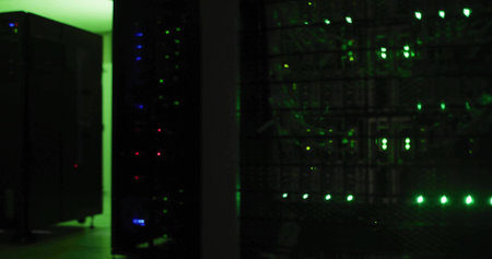 Rack-mounted servers pulsing LED lights in server room corridor, with switches and patch cables....