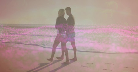 White female and Hispanic male walking along sandy shore at water edge, with sunglasses, footprints. Romantic, sunset, silhouette, coastal, leisure, serenity, natureの写真素材
